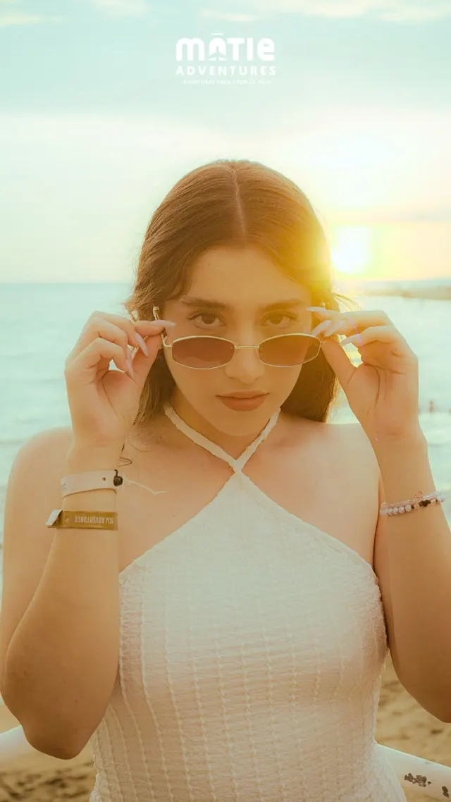 Alumna con brazalete MATIE bajándose los lentes de sol frente al mar