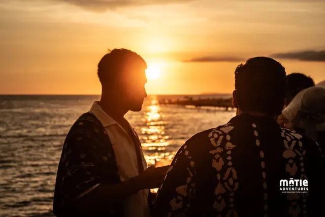 Silueta de dos amigos platicando a contraluz del atardecer