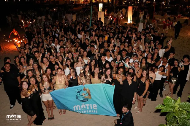 Class with the MATIE flag on the beach at night