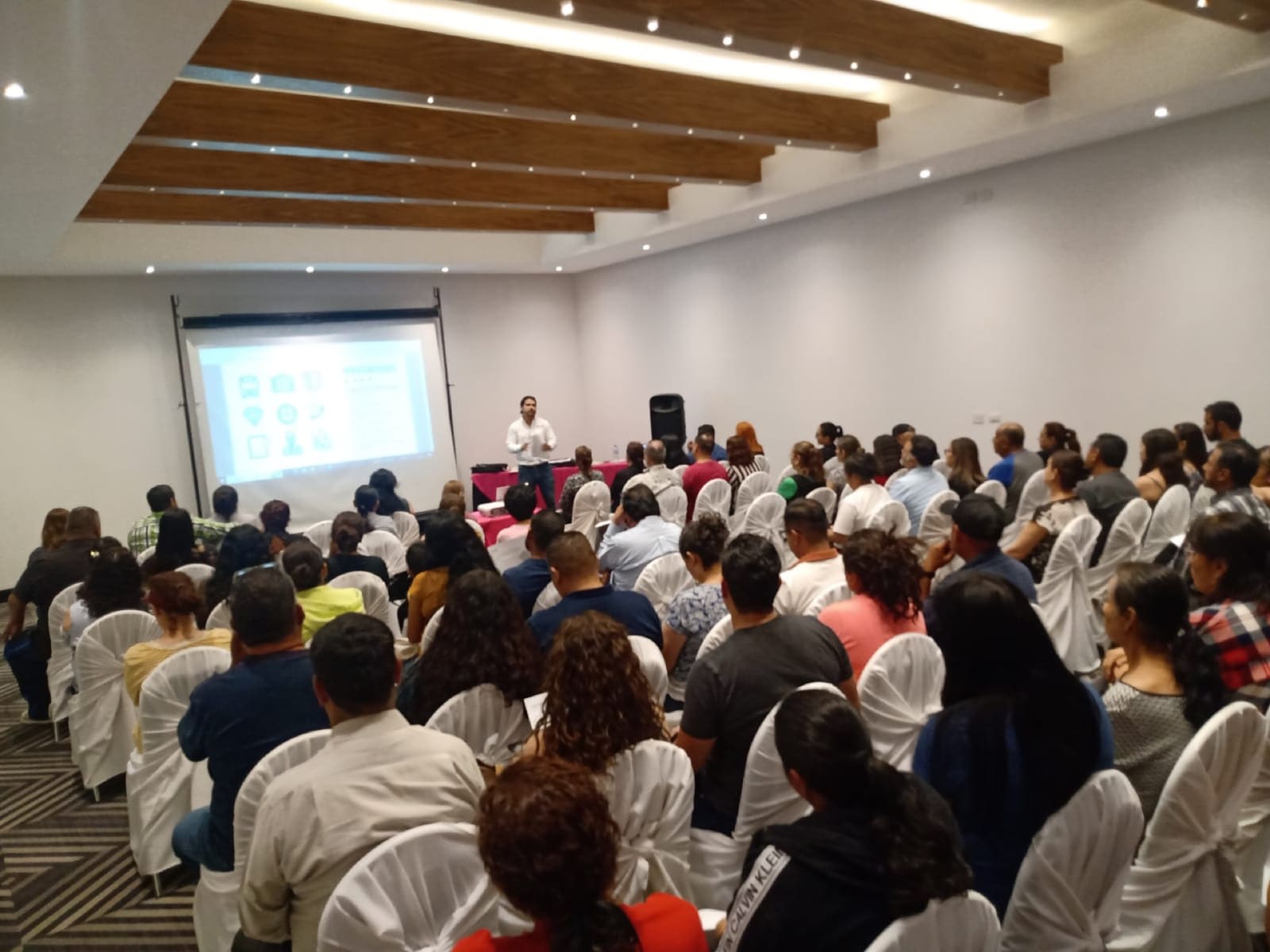 Salón lleno de padres de familia durante una junta informativa de MATIE antes del viaje