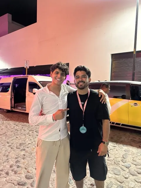 Staff MATIE con un viajero frente a la van del viaje, de noche
