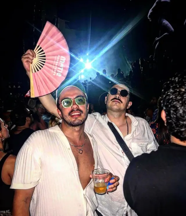 Clientes MATIE de noche con un abanico rosa de la marca en alto