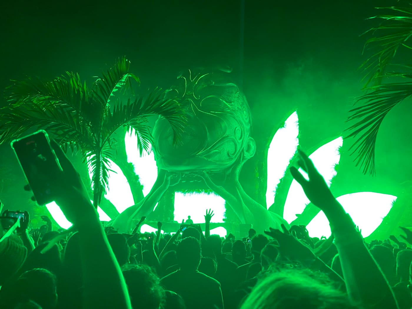 Green-lit stage with a crowd celebrating at a MATIE festival in Tulum