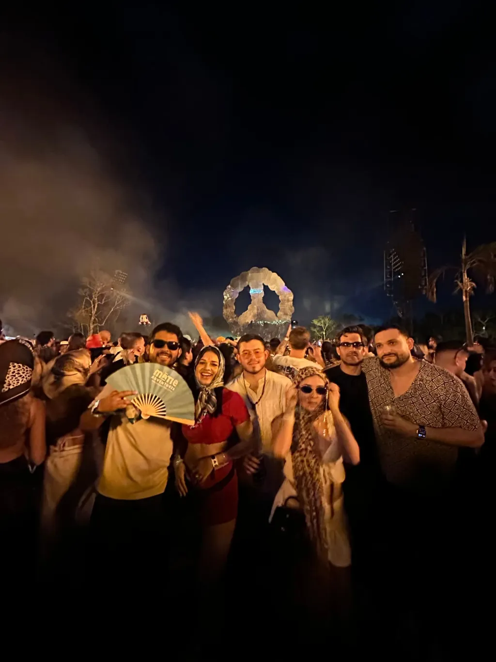 Grupo de viajeros MATIE de noche en el festival, con el abanico de la marca y el arco iluminado al fondo