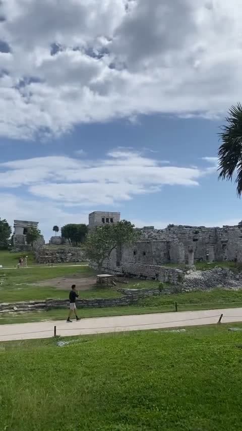 Las ruinas mayas de Tulum en un día despejado, con un visitante caminando entre las construcciones